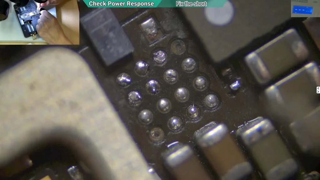 Microscope image showing two damaged solder pads on the backlight circuit after removing burned material from the motherboard.