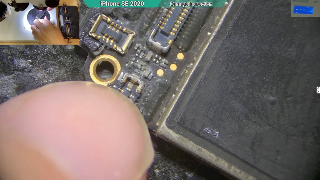 Microscope view of corrosion on the circuit of a water-damaged iPhone near speaker area