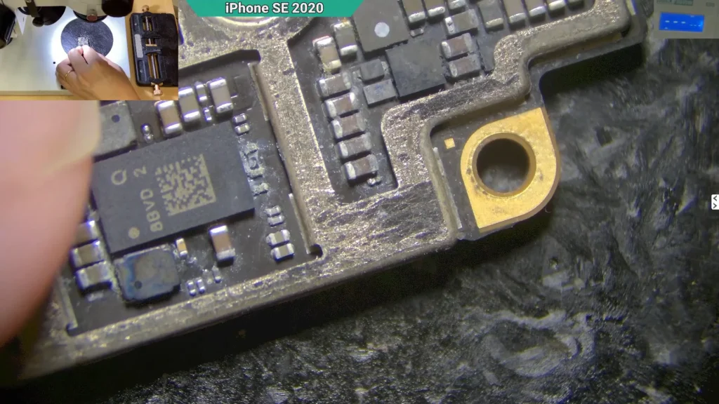 Microscope close-up showing corrosion around the backlight circuit components on a water-damaged iPhone motherboard.