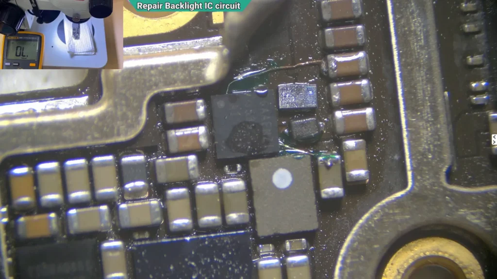 Microscope image showing a replacement backlight IC being soldered onto the repaired iPhone motherboard using hot air.