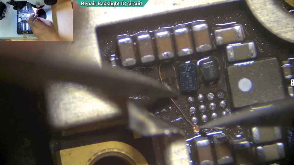 Microscope image showing replacement solder pads being positioned onto the damaged backlight circuit of an iPhone motherboard.