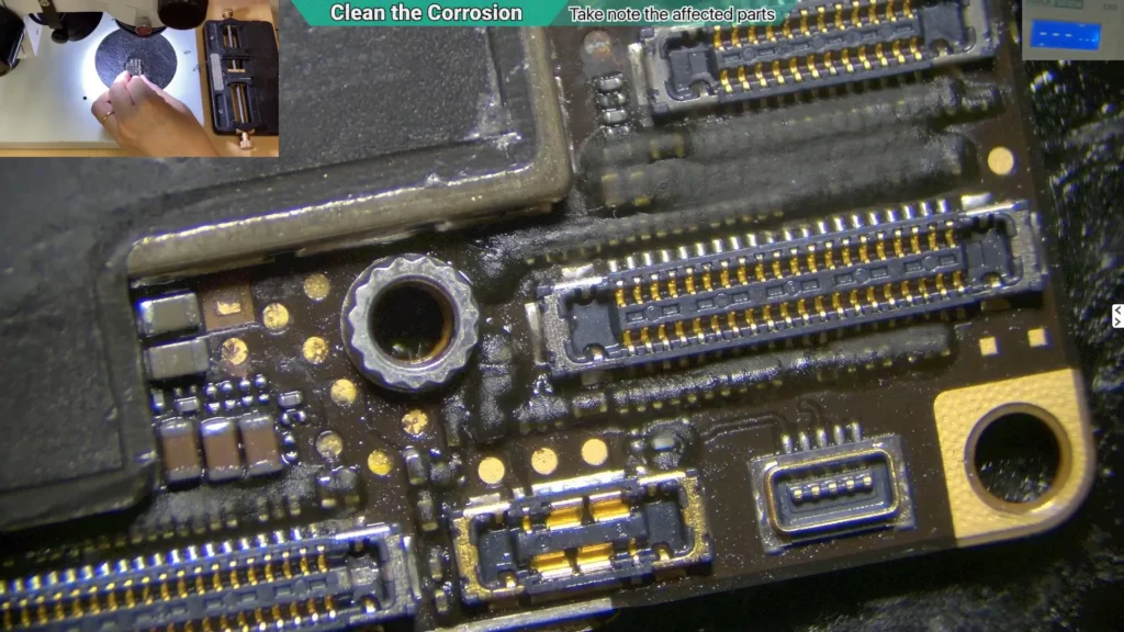 Close-up microscope image of a cleaned area on a water-damaged iPhone motherboard following corrosion removal on battery connector