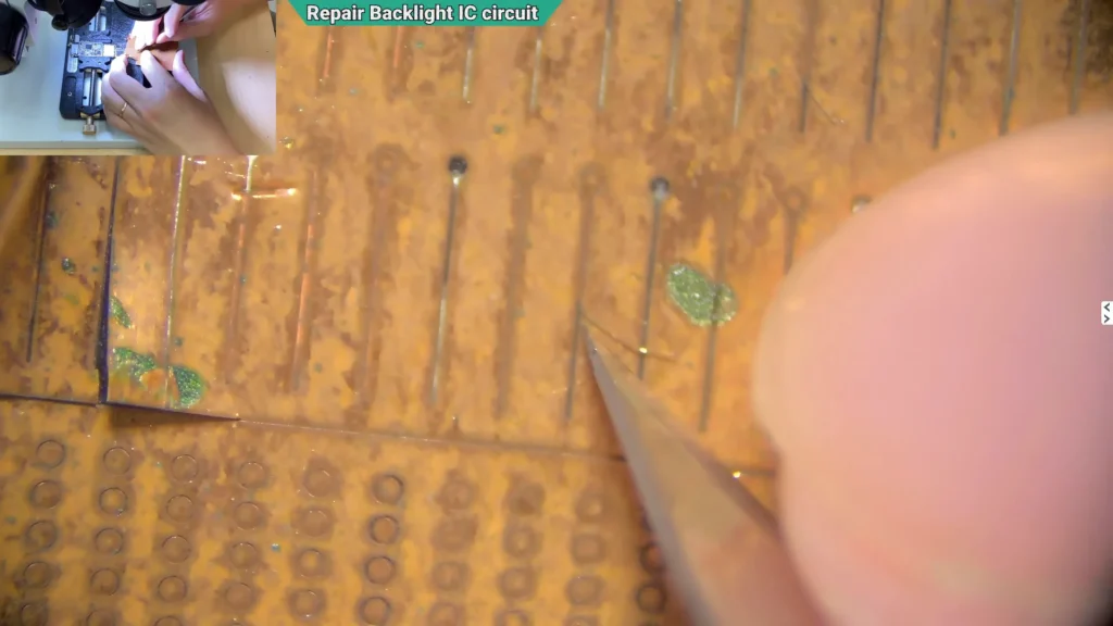 Microscope image showing a solder pad repair kit being cut to create replacement pads for a damaged iPhone motherboard.
