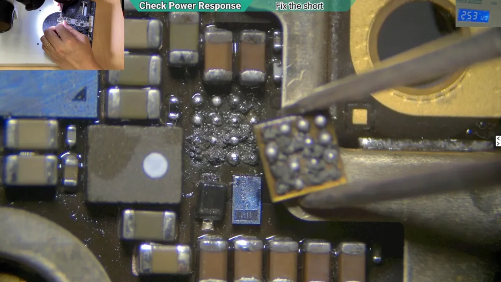 Microscope image showing severe corrosion and burn damage beneath the removed backlight IC on a water-damaged iPhone motherboard.